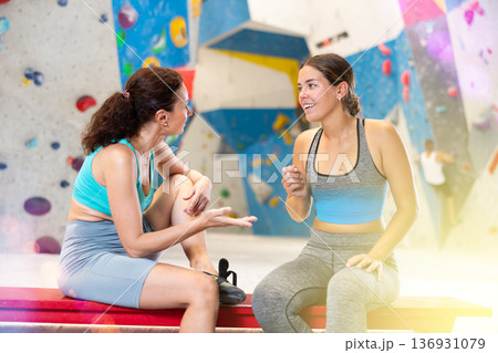 Rest after rock climbing - two friends exchange impressions about training at climbing wall Rest after rock climbing - two friends exchange impressions about training at climbing wall 136931079