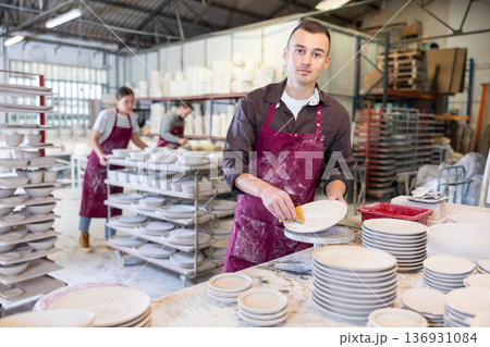 Young man cleaning blanks of ceramic products Young man cleaning blanks of ceramic products 136931084
