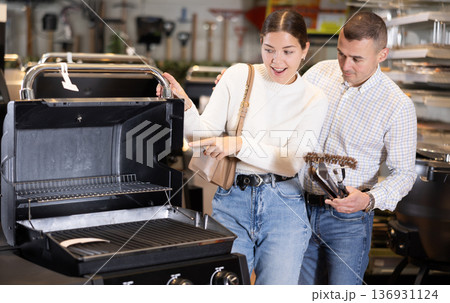 In store, married couple inspect mobile grill, buys barbecue device In store, married couple inspect mobile grill, buys barbecue device 136931124
