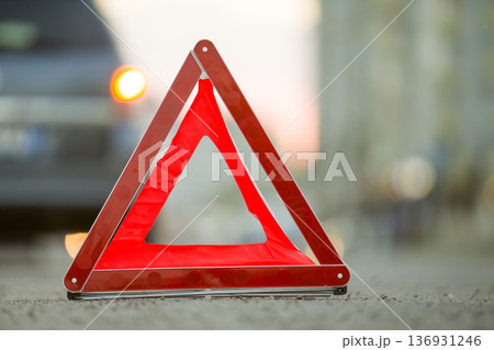 Red emergency triangle stop sign and broken car on a city street. 136931246