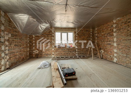 Interior of unfinished brick house with concrete floor and bare walls ready for plastering under construction. Real estate development Interior of unfinished brick house with concrete floor and bare walls ready for plastering under construction. Real estate development 136931253