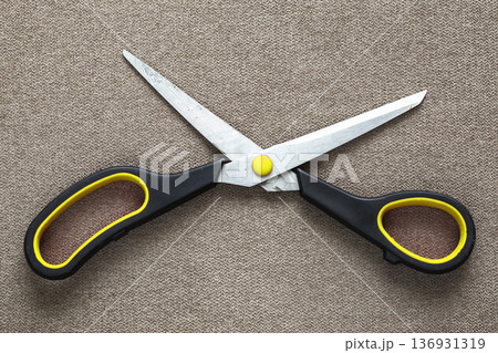 Close-up of sharp steel metal scissors isolated on light cloth copy space background. Household equipment, office or school tools. Close-up of sharp steel metal scissors isolated on light cloth copy space background. Household equipment, office or school tools. 136931319