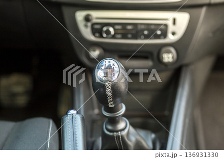 Luxurious car black leather interior. Close-up detail of handbrake manual brake and gearshift stick on blurred dashboard background. Transportation, design, modern technology concept. 136931330