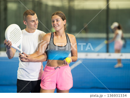 Young girl learns to play padel under guidance of male coach 136931334