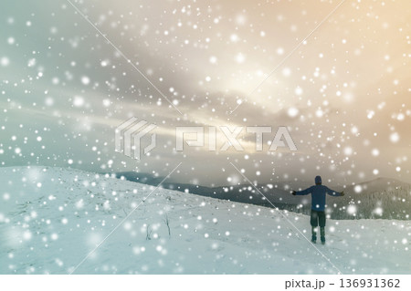 Back view of tourist hiker in warm clothing with backpack standing with raised arms on clearing covered with snow on spruce forest mountain and cloudy sky copy space background. Back view of tourist hiker in warm clothing with backpack standing with raised arms on clearing covered with snow on spruce forest mountain and cloudy sky copy space background. 136931362