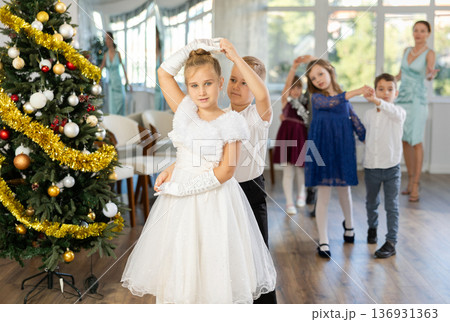 Christmas ball - beautifully dressed children dance the Viennese waltz near New Year tree 136931363