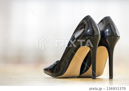 Pair of fashionable high heel lacquer leather black female shoes isolated on light copy space background. Style and fashion, modern footwear concept. Pair of fashionable high heel lacquer leather black female shoes isolated on light copy space background. Style and fashion, modern footwear concept. 136931370