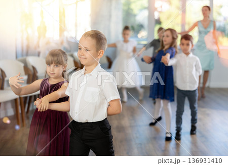 Little children in elegant dresses standing in pairs in dance pose in school hall 136931410