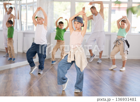 In sports studio, childrens team learns hip-hop dance accompanied by experienced man teacher 136931481