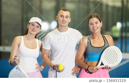 Two women and man posing on tennis court Two women and man posing on tennis court 136931529