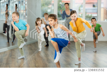 Group of preteen girls and boys enjoying active dance movement in studio Group of preteen girls and boys enjoying active dance movement in studio 136931532