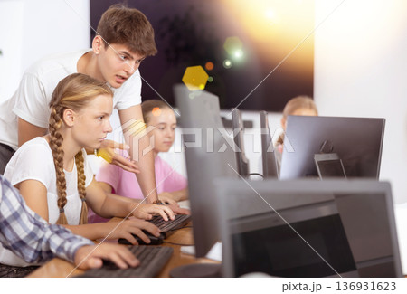 Guy teacher teaches girl student how to use computer 136931623