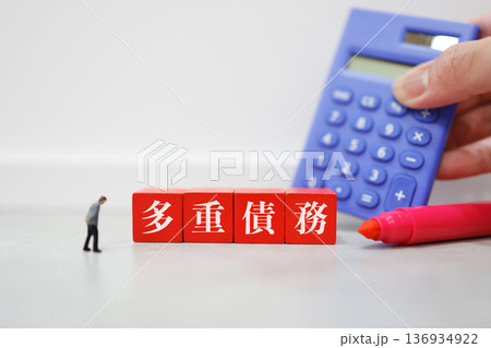 電卓と男性人形の多重債務イメージ。	 136934922