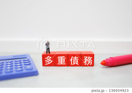 電卓と男性人形の多重債務イメージ。	 136934923