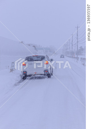 吹雪の豪雪地帯を走るオールシーズンタイヤを履いたSUV 吹雪の豪雪地帯を走るオールシーズンタイヤを履いたSUV 136935597