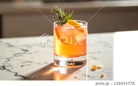 Orange cocktail with ice and orange peel in a glass on a marble table. Refreshing summer drink or alcoholic beverage. 136935778