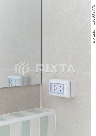 Electrical outlet wall bathroom mirror tile white modern clean safety interior design. Electrical outlet light colored tiled bathroom wall with mirror reflecting clean and modern interior design 136935779