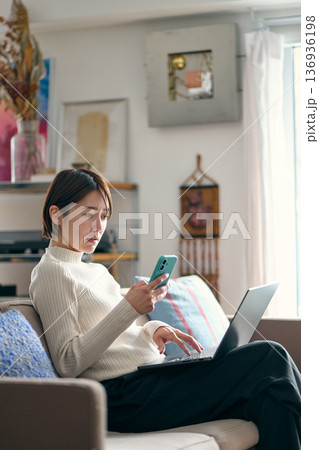 スマートフォンを操作しながら不安な表情をする女性 136936198