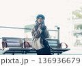 バス停で座ってスマートフォンを見る冬の女性 136936679