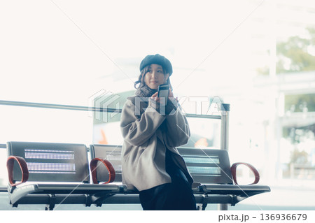 バス停で座ってスマートフォンを見る冬の女性 バス停で座ってスマートフォンを見る冬の女性 136936679