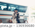 バス停で座ってスマートフォンを見る冬の女性 136936680
