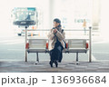 バス停で座ってスマートフォンを見る冬の女性 136936684