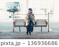 バス停で座ってスマートフォンを見る冬の女性 136936686