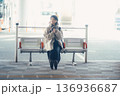バス停で座ってスマートフォンを見る冬の女性 136936687