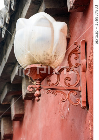 Vintage wall sconce with ornate red bracket 136937933