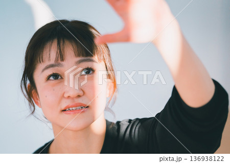 太陽の光を手で遮る笑顔の女性 136938122