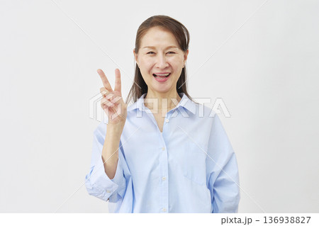 白背景でピースサインをする女性 136938827
