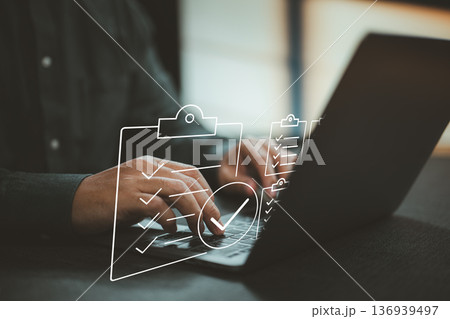 Person using laptop with digital checklist icons overlay for task management and productivity Person using laptop with digital checklist icons overlay for task management and productivity 136939497