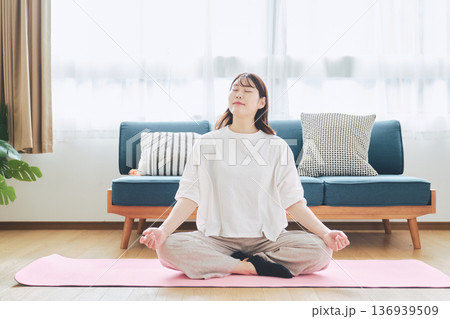 自宅で瞑想と深呼吸をする30代女性のマインドフルネスライフスタイル 136939509