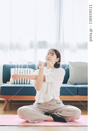 自宅で体をほぐすストレッチをする30代女性の健康習慣 自宅で体をほぐすストレッチをする30代女性の健康習慣 136939511