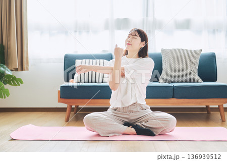 自宅で体をほぐすストレッチをする30代女性の健康習慣 自宅で体をほぐすストレッチをする30代女性の健康習慣 136939512