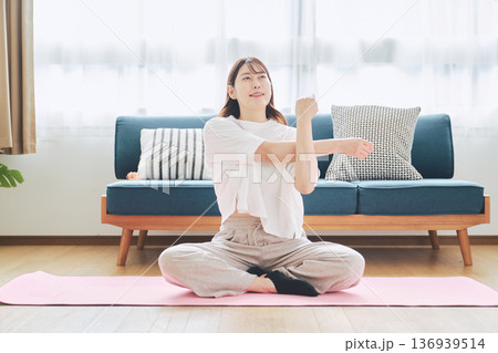 自宅で体をほぐすストレッチをする30代女性の健康習慣 136939514