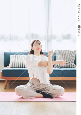 自宅で体をほぐすストレッチをする30代女性の健康習慣 自宅で体をほぐすストレッチをする30代女性の健康習慣 136939515