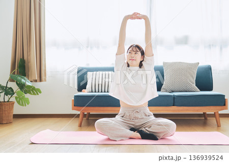 自宅で体をほぐすストレッチをする30代女性の健康習慣 自宅で体をほぐすストレッチをする30代女性の健康習慣 136939524
