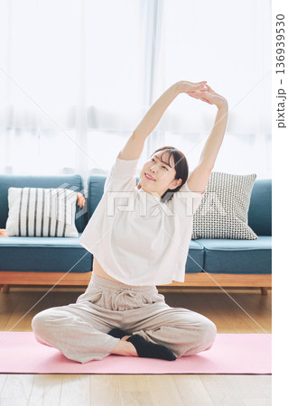 自宅で体をほぐすストレッチをする30代女性の健康習慣 136939530