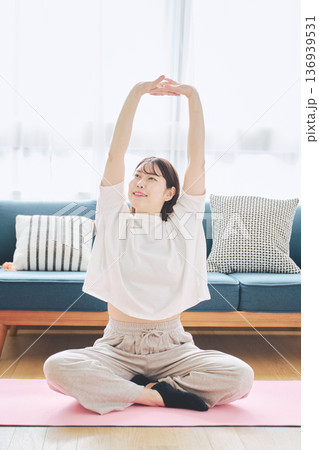 自宅で体をほぐすストレッチをする30代女性の健康習慣 136939531