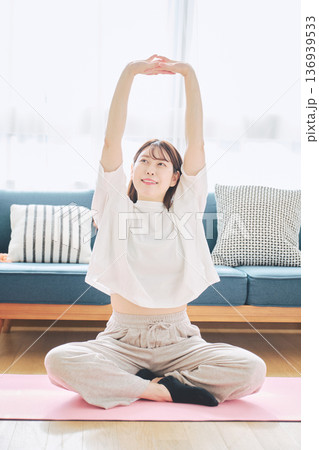 自宅で体をほぐすストレッチをする30代女性の健康習慣 136939533