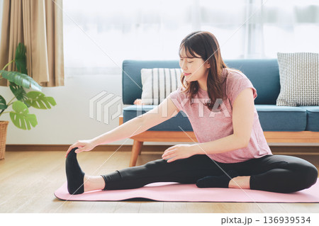 自宅で体をほぐすストレッチをする30代女性の健康習慣 自宅で体をほぐすストレッチをする30代女性の健康習慣 136939534
