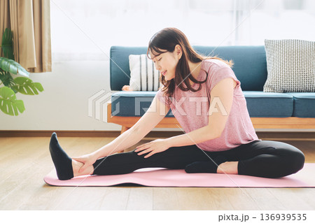 自宅で体をほぐすストレッチをする30代女性の健康習慣 自宅で体をほぐすストレッチをする30代女性の健康習慣 136939535
