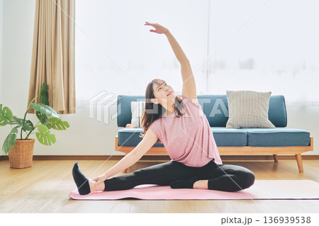 自宅のリビングでヨガポーズをする30代女性のフィットネスライフ 136939538