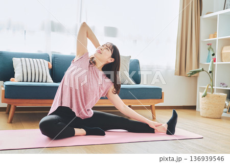 自宅のリビングでヨガポーズをする30代女性のフィットネスライフ 136939546