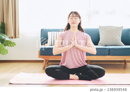 自宅のリビングでヨガポーズをする30代女性のフィットネスライフ 136939548