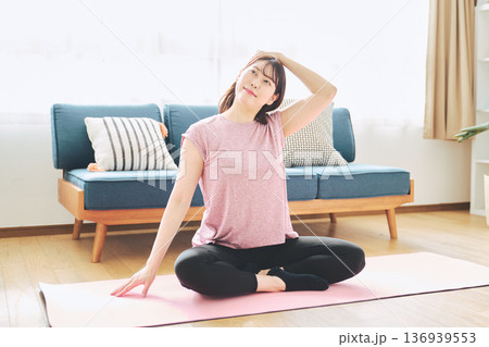 自宅で体をほぐすストレッチをする30代女性の健康習慣 自宅で体をほぐすストレッチをする30代女性の健康習慣 136939553