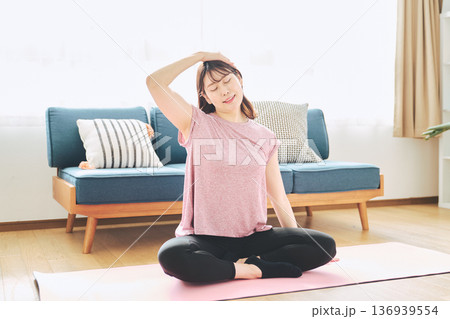 自宅で体をほぐすストレッチをする30代女性の健康習慣 136939554