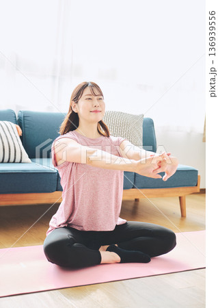 自宅で体をほぐすストレッチをする30代女性の健康習慣 自宅で体をほぐすストレッチをする30代女性の健康習慣 136939556