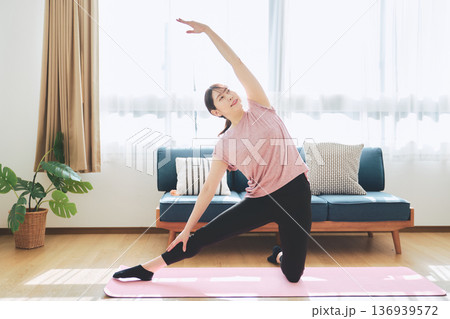 自宅のリビングでヨガポーズをする30代女性のフィットネスライフ 自宅のリビングでヨガポーズをする30代女性のフィットネスライフ 136939572